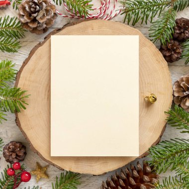 Kış Noel Kompozisyonu ve tahta masa üzerinde boş bir kart. Noel ve Yeni Yıl tebrik kartı şablonu köknar ağacı dalları, çam kozalakları ve süslemelerle dolu. Tatil modeli..