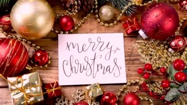 Üzerinde el yazısıyla yazılmış bir kart Merry Noel süsleri olan ahşap masa üstü görüntüsü yakınlaştır