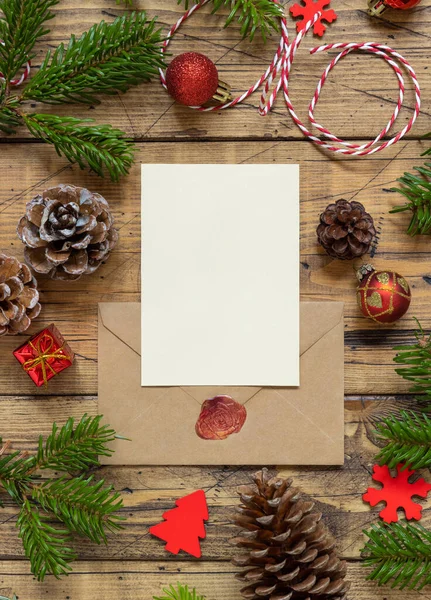 冬天的圣诞作文 一张空白的卡片和一个木制桌子上的信封躺着 圣诞和新年贺卡模板与冷杉树枝 松果和圣诞装饰顶部视图 假日恶作剧 — 图库照片