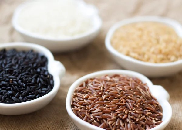 Variedade de arroz em tigelas em mesa de madeira — Fotografia de Stock