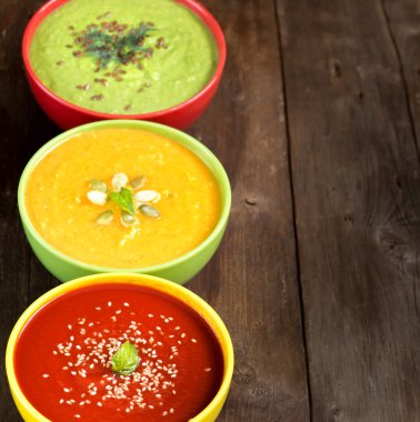 Ahşap bir masa üzerinde üç taze çorbalar