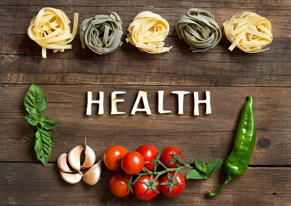 Pasta, vegetables and herbs on wood — Stock Photo, Image