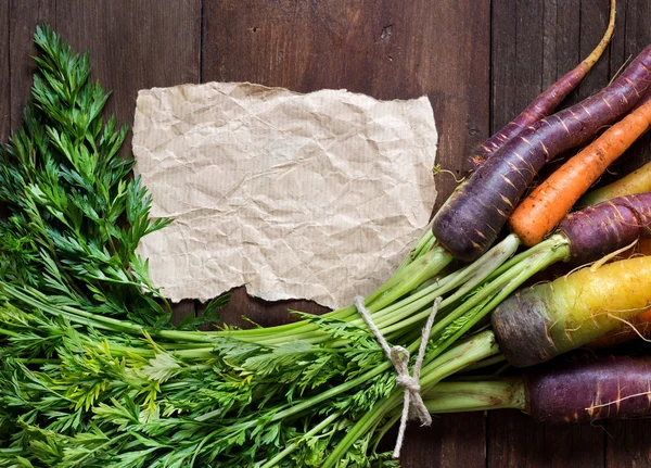 Fresh organic rainbow carrots and paper — Stock Photo, Image