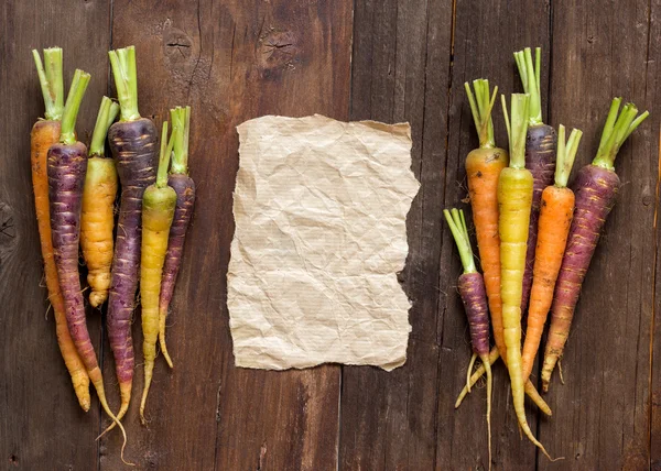 Fresh organic rainbow carrots and paper — Stock Photo, Image