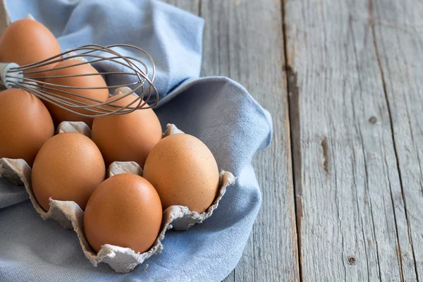 Chicken eggs and a whisk — Stock Photo, Image