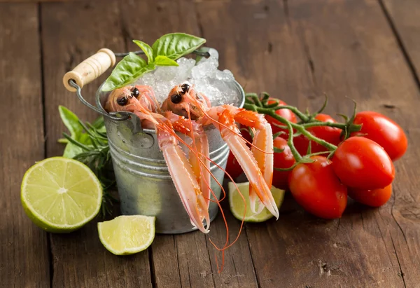 Raw langoustine in a bucket with vegetables and herbs — Stock Photo, Image