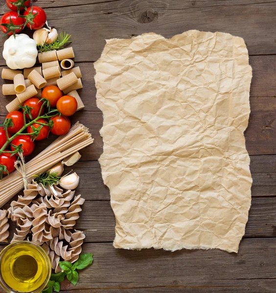 Olive oil, pasta, garlic and tomatoes  with craft paper — Stock Photo, Image