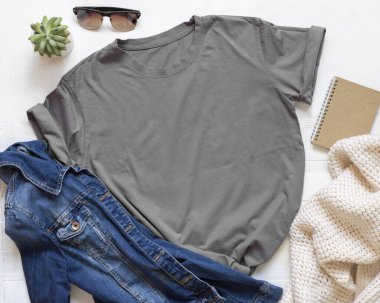 Kot ceketle spor ayakkabısı arasındaki kömür grisi uniseks tişörtü beyaz ahşap üst manzara, maket. Kıyafetler düz bir şablon. Aksesuarlarla yaz tatili. Gömlek baskısı sunumu 