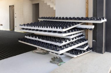 Yeni bir binada yer ısıtması, siyah yalıtım çarşafları. Yeni bir evde, iç mimaride yer altı ısıtma sistemi.