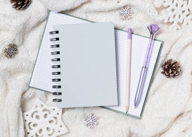 Kar taneleri ve çam kozalaklarının yanında beyaz örülmüş süveter üzerine gri boş spiral defter, Noel ya da yeni yıl modeli, kopyalama alanı. Okul veya süt ürünleri için sarmal ciltli ders kitabı, sıcak kış möö 'sü