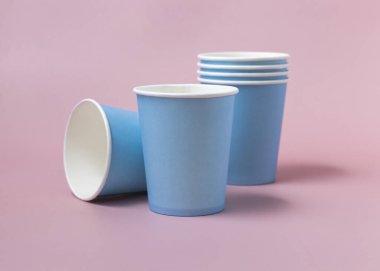 Tek kullanımlık açık mavi bardaklar pembe yakın plan çekimde izole edilmiş. Boş karton kahve fincanları. Çevre dostu tek kullanımlık kapaksız kalkış konteynırları, plastikten ayrıştırılabilir materyal yok.