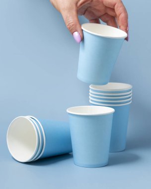 Tek kullanımlık açık mavi kağıt bardağı olan kadın el yakından izole edilmiş, reklam alanı olan bir model. Boş karton kahve fincanı. Kapaksız çevre dostu tek kullanımlık konteynırlar