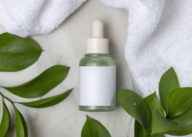 Beyaz banyo havlusunun yanında kapalı cam damlatıcı şişesi ve taşın üstünde yeşil yapraklar. Etiketli markasız kozmetik ambalaj modeli. Tarafsız banyo sahnesinde cilt bakımı, kopyalama alanı