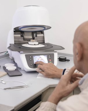 Ortodont erkekler diş implantı diş minesi pişirmek için diş seramik fırını programlarlar. Takma diş, taç ya da kaplama yapımında kullanılan profesyonel ekipman ve işlemler. Diş protezinde gelişmiş teknoloji.