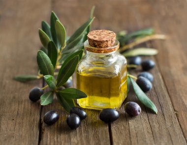 Zeytinyağı ve taze zeytin ahşap arka plan üzerinde