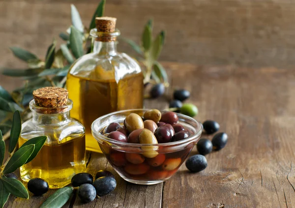 Aceite de oliva y aceitunas sobre fondo de madera — Foto de Stock