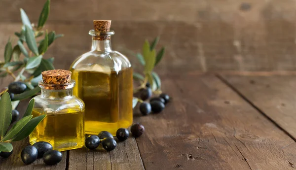 Aceite de oliva y aceitunas frescas sobre fondo de madera — Foto de Stock