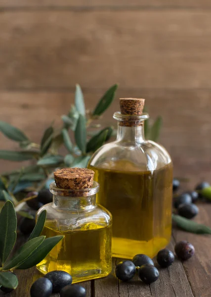 Aceite de oliva y aceitunas sobre fondo de madera — Foto de Stock