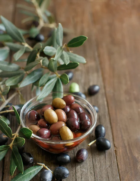 Aceitunas frescas y rama de olivo sobre fondo de madera — Foto de Stock