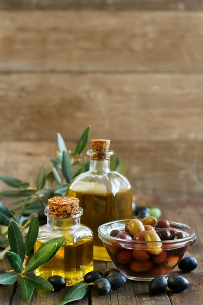 Aceite de oliva y aceitunas sobre fondo de madera — Foto de Stock