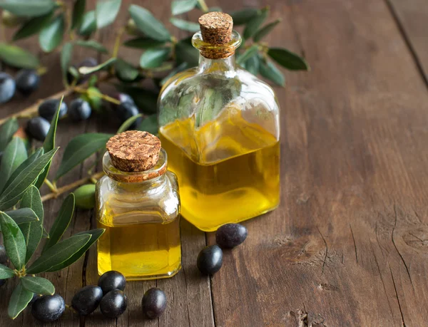 Aceite de oliva y aceitunas frescas sobre fondo de madera — Foto de Stock