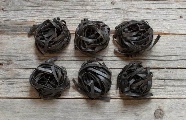 Tagliatelles noires sur une vieille table en bois — Photo