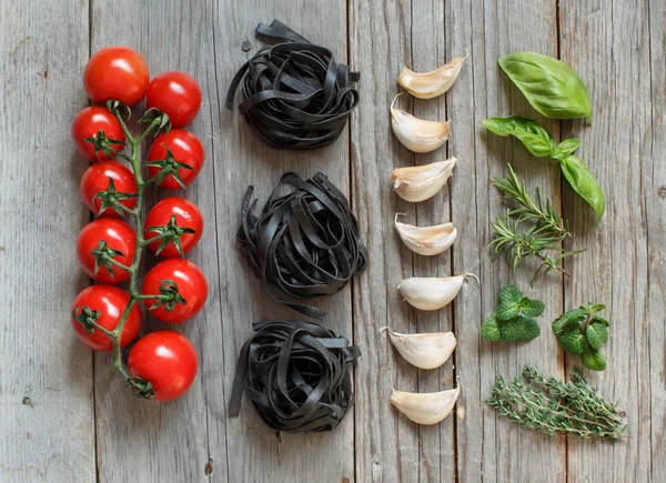 Macarrão Tagliatelle preto com tomate cereja, alho e ervas — Fotografia de Stock