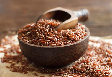 Çiğ kırmızı pirinç bir kase bir tahta kaşıkla 