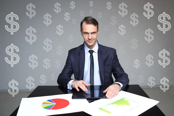 Hombre de negocios sentado en la mesa. dólar signos en el fondo — Foto de Stock