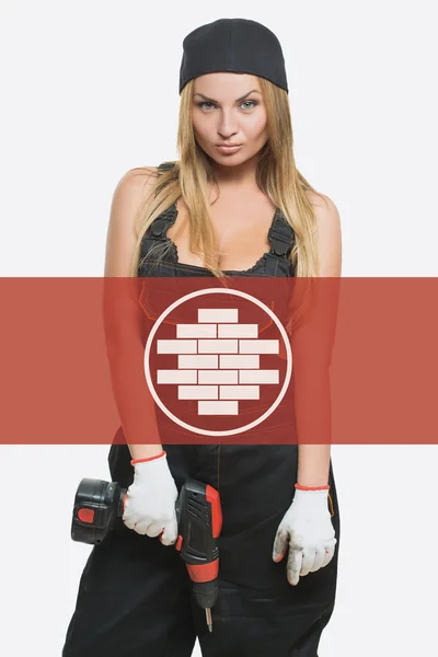 Sexy female holding a cordless screwdriver. brickwork icon in the background woman. — ストック写真