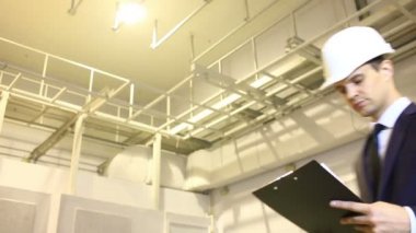 takım elbise ve kask adam. Bina olup olmadığını denetler. plana danışır