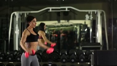fitness salonunda bankta poz kız. Dumbbell yükseltir
