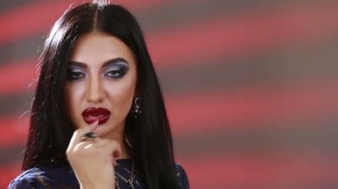 Closeup face of a beautiful sensuality girl with blue eye makeup sends a air kiss. Portrait of a caucasian woman with positive emotions. finger in mouth