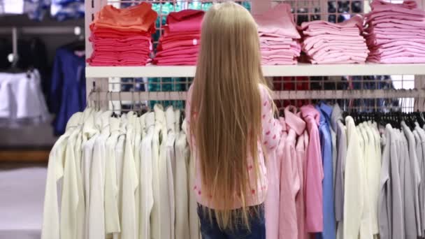 Menina bebê olhando para roupas na loja da moda — Vídeo de Stock