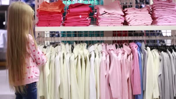 Niña mirando la ropa en la tienda de moda — Vídeo de stock