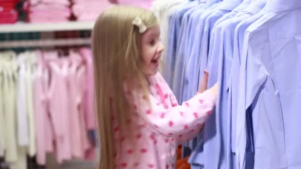 Baby girl looking at clothes in fashionable shop — Stock Video