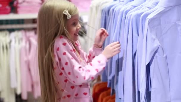 Menina bebê olhando para roupas na loja da moda — Vídeo de Stock