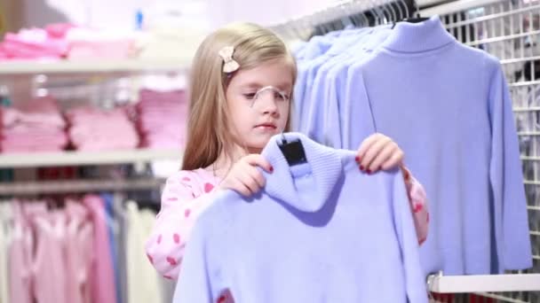 Bambina guardando i vestiti nel negozio alla moda — Video Stock