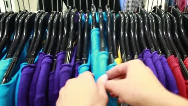 Покупатель выбирает футболку в бутике — стоковое видео