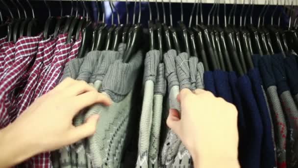 Мужчина покупатель ищет футболки в магазине моды — стоковое видео