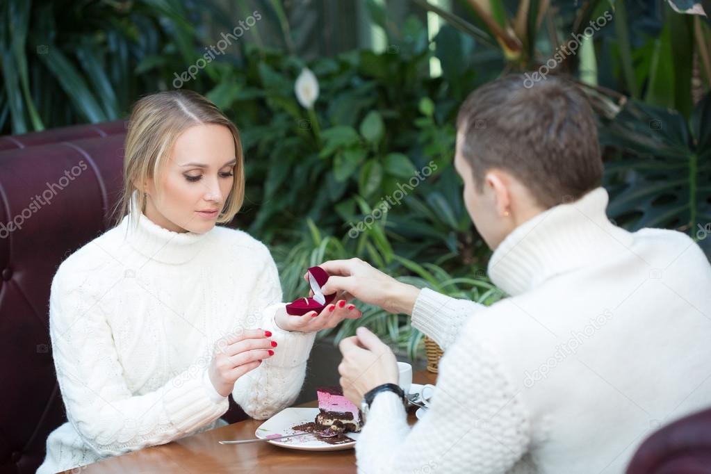 restaurant, couple and holiday concept - excited young woman looking at boyfriend with engagement ring