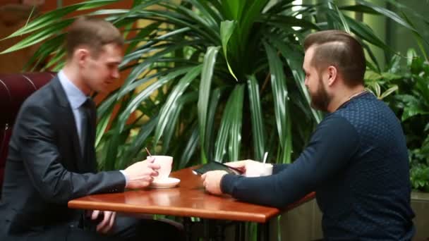 Два бизнесмена пожимают руки в кафе — стоковое видео