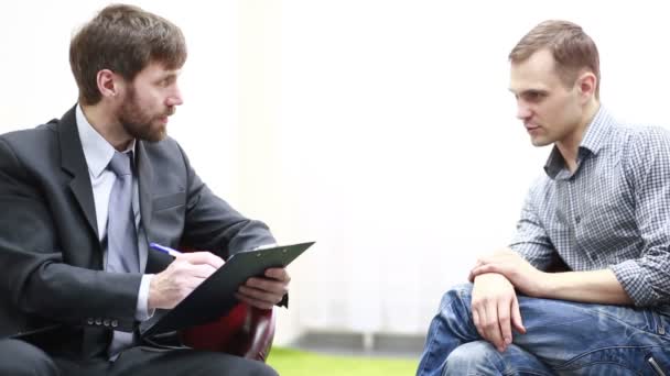 Sad young man talking with psychologist. — Stock Video