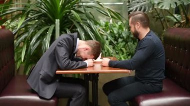 Neşeli erkek meslektaşları kafede masada oturuyorsun.