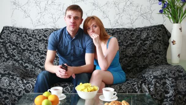 Giovane coppia guardando la TV su un divano a casa — Video Stock