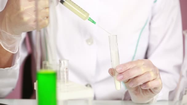 Female chemist comparing test tubes with chemicals. protective glasses — Stock Video