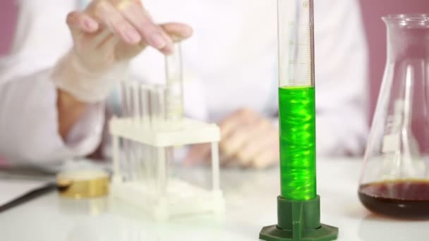 여성 화학자는 화학 물질과 시험관을 비교입니다. 보호 안경 — 비디오