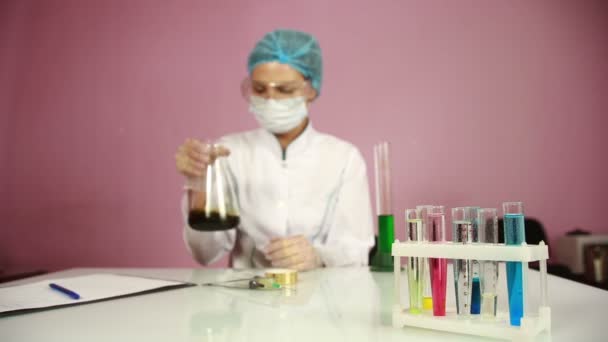 Química feminina comparando tubos de ensaio com produtos químicos. óculos de proteção — Vídeo de Stock