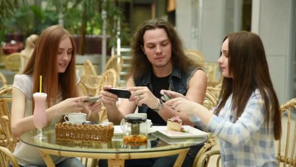 La tecnología, el estilo de vida y el concepto de la gente - amigos felices con teléfonos inteligentes tomando fotos de la comida en el restaurante — Vídeo de stock