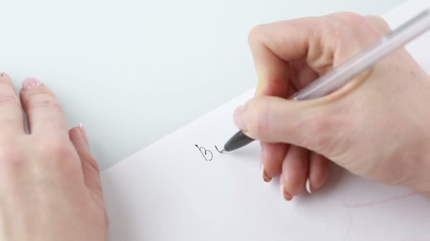 Writing woman hand on a white background. Woman writes on a paper business plan — Stock Video